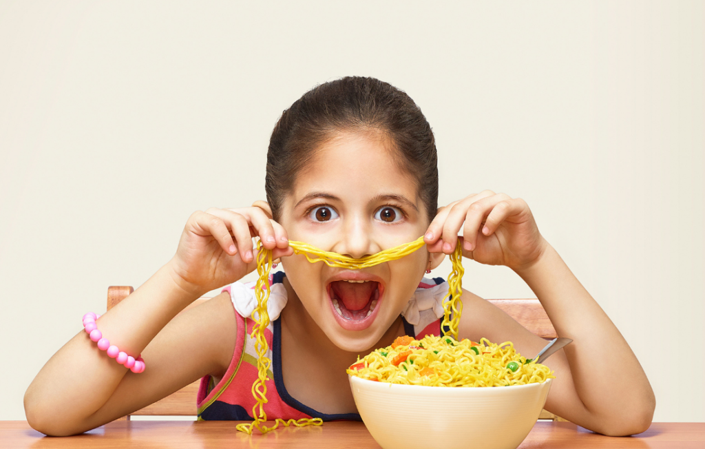 Kid making a funny face with a bowl of ramen noodles